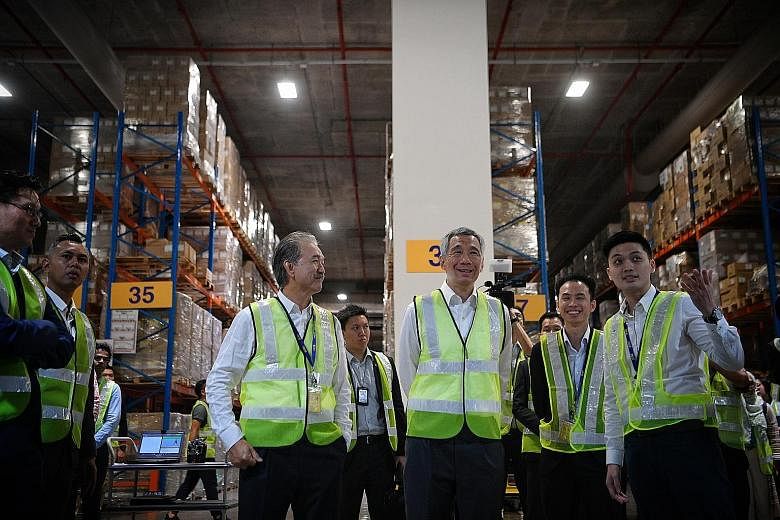 Prime Minister Lee Hsien Loong touring logistics giant YCH's flagship headquarters, Supply Chain City, in Jurong West yesterday with (from left) YCH chairman Robert Yap; head of operations innovation Khoo Ngiap Seng; and Mr Ngoh Jun Dat, who is with 