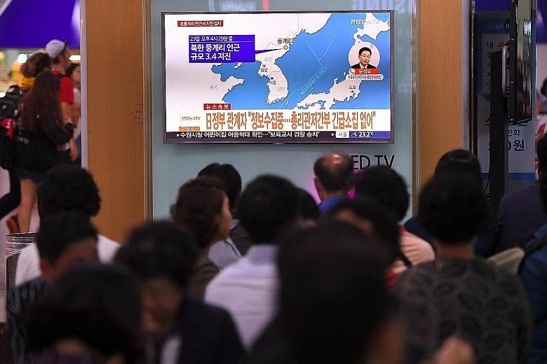 People crowding around a TV screen showing the epicentre of the quake at a railway station in Seoul yesterday. News of the quake coincided with Iran's announcement of its successful test of a new medium-range missile.