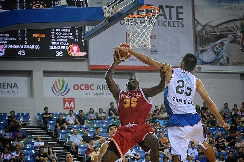 Singapore Slingers' Ryan Wright shoots under the close attention of the Shanghai Sharks' Zhang Zhaoxu. The centre scored 19 points, but his effort was in vain as the local basketball team lost 67-73 to the defending champions Sharks in yesterday's Me