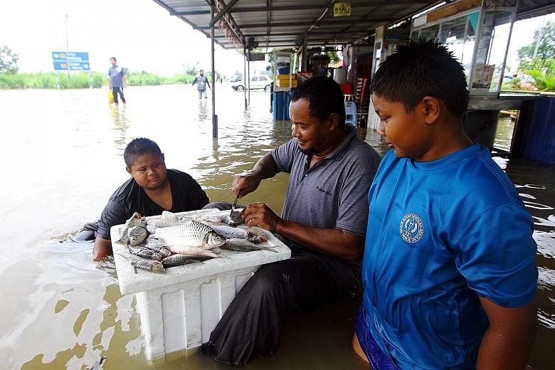 Mr Norzamlan Abu Seman, 30, with some of the 10kg of fish he caught when rain water submerged a road in Taman Seri Lancang Mata Ayer in Perlis. A total of 1,672 people were evacuated in the state.