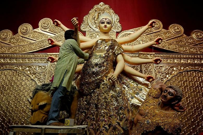 An artisan decorating a gold sari on an idol of Hindu goddess Durga, at a temporary platform called the pandal, ahead of the Durga Puja festival in Kolkata, India.