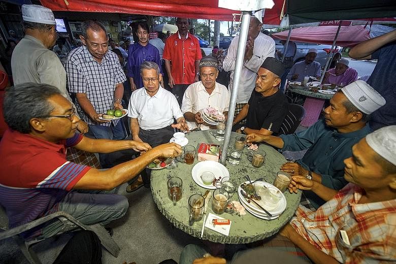 International Trade and Industry Minister Mustapa Mohamed (seated, second from left), of the ruling Umno, mingling with villagers as part of his visit to Kampung Kelaboran in Tumpat, Kelantan, yesterday. Although the opposition PAS currently controls