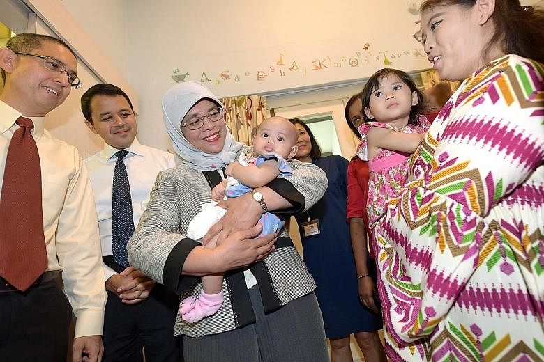 President Halimah Yacob, with Senior Parliamentary Secretary for Social and Family Development Muhammad Faishal Ibrahim (left) and MP Christopher De Souza (second from left), at HCSA Dayspring in Turf Club Road yesterday. Madam Halimah is cradling fo