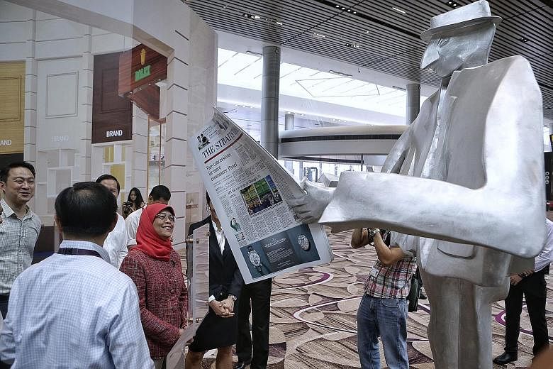President Halimah Yacob viewing sculptures in the departure transit area during her visit to Changi Airport's Terminal 4 yesterday. She also viewed some of the technology being used to boost efficiency and security.
