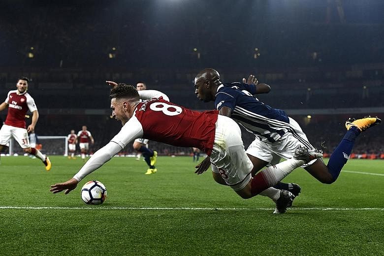 Arsenal's Aaron Ramsey is fouled by West Brom's Allan Nyom for a penalty, from which the Gunners score to wrap up a 2-0 win in the English Premier League match at the Emirates Stadium in London. 