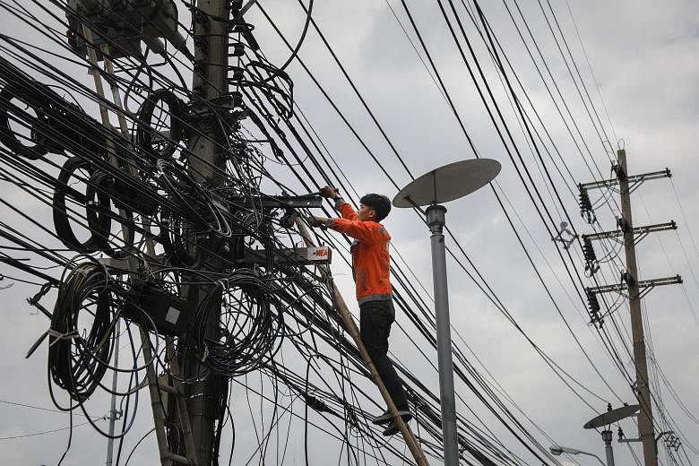 A worker cutting a mass of cluttered power lines in Bangkok as the Thai capital prepares to move its cables underground to improve the look of the city and also as a precaution against the concrete power poles collapsing onto the street. Thailand's C