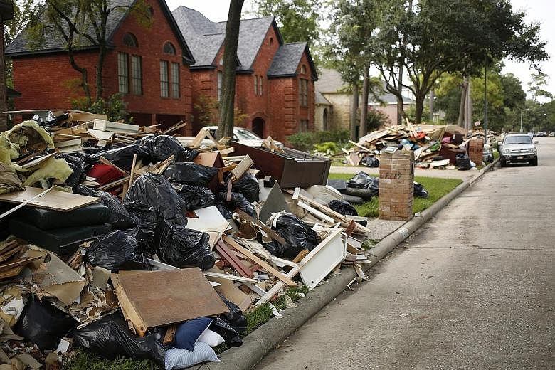 Piles of debris outside homes that were flooded after Hurricane Harvey hit the area of Spring in Texas. Harvey, which struck Texas last month, and Hurricane Irma, which hit Florida early this month, temporarily curbed economic activity but rebuilding
