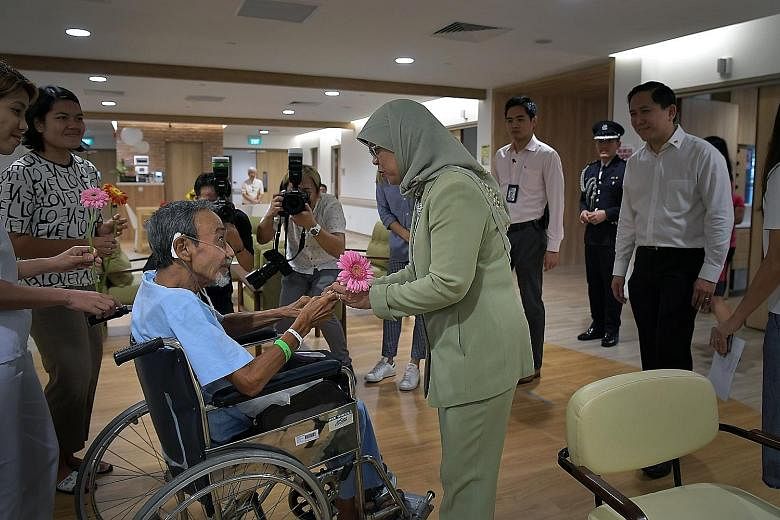 Freelance photographer Alan Lee, 69, who has an exhibition of photos showcasing the everyday lives of his fellow patients at Assisi Hospice, meeting President Halimah Yacob yesterday when she visited the facility in Thomson Road. In a Facebook post, 