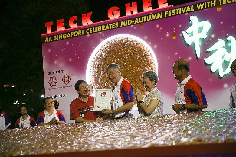 Prime Minister Lee Hsien Loong, accompanied by his wife, Mrs Lee, being presented with a Singapore Book of Records certificate for the most number of mooncakes displayed, at Teck Ghee Lantern Night 2017 yesterday. A total of 40,100 miniature mooncake