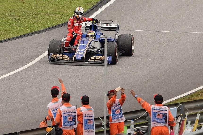 Ferrari's Sebastian Vettel is given a lift by Pascal Wehrlein of Sauber after he collided with Lance Stroll's Williams during the slow-down lap at Sepang.