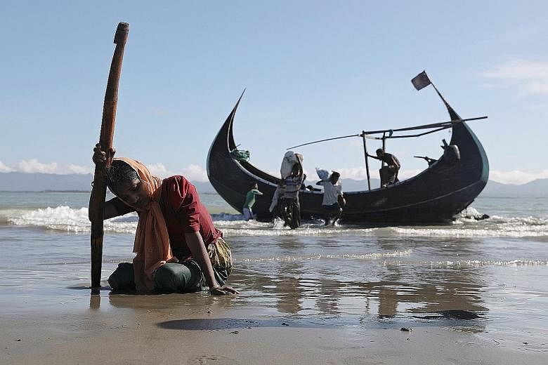 A refugee woman collapses from exhaustion after reaching the shores of Shah Porir Dwip, Bangladesh, on Sunday in a wooden boat from Myanmar.