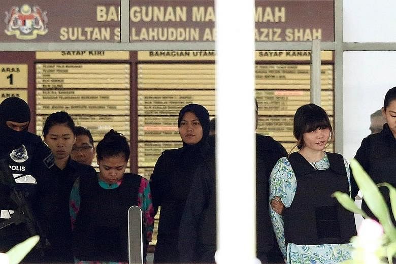 Police officers escorting Siti Aisyah (at left) and Doan Thi Huong as they left the Shah Alam High Court yesterday. The two women, who are on trial for Mr Kim Jong Nam's murder, allegedly smeared his face with the VX nerve agent at Terminal 2 of KLIA