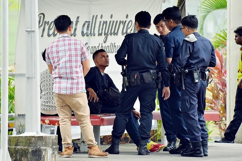 The two men (seated, one partially blocked) being questioned at the entrance to Bishan Depot yesterday. The men, who are believed to be foreigners and have been released, wanted to take photos of the place, and started using their cameras at the gate