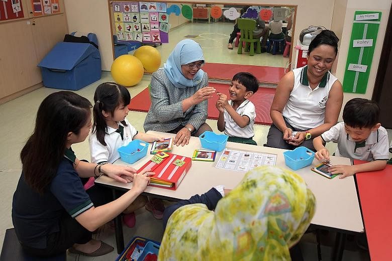 President Halimah Yacob interacting with six-year-olds (from left) Eureka Chong, Jothy Kanna Deepak and Ivan Ong at Rainbow Centre Yishun Park School. With them are (from far left) early intervention programme assistant director Janice Leong and teac