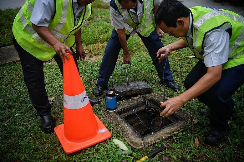 Above: PUB staff using a leak noise correlator to pinpoint the leak spot along the pipe at Block 222, Bukit Batok East Avenue 3, where a pipe burst on Sunday. Below: On Sept 26, a pipe leak sent up a fountain of water at the junction of Bukit Batok W