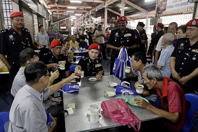 Federal Reserve Unit commander Wan Abdullah Ishak (centre) and other officials from Malaysia's riot police unit mingling with George Town residents on Tuesday as part of a community policing programme to forge closer ties with citizens and change pub