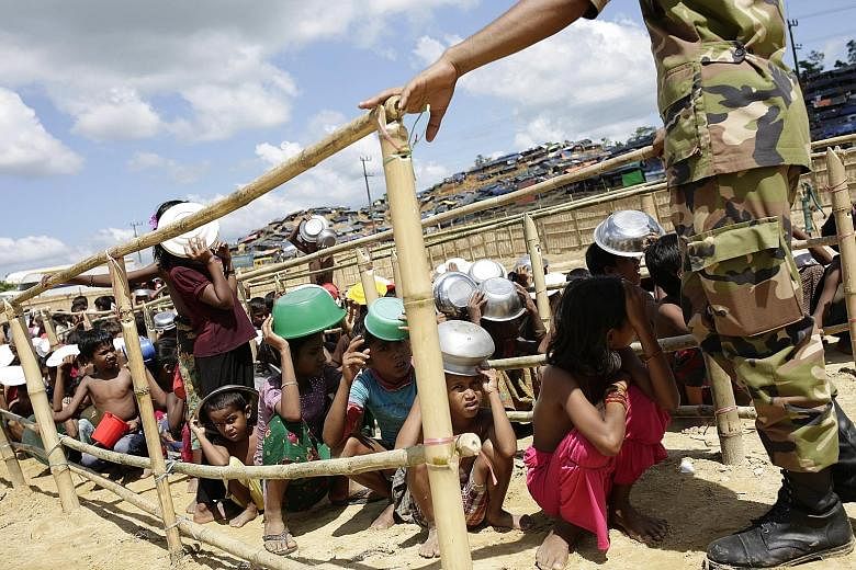 Rohingya children queueing to collect food in a camp in Ukhiya, Cox's Bazar, Bangladesh, yesterday. More than half of an estimated 809,000 refugees are children. About 24,000 pregnant women need maternity care, aid agencies say.