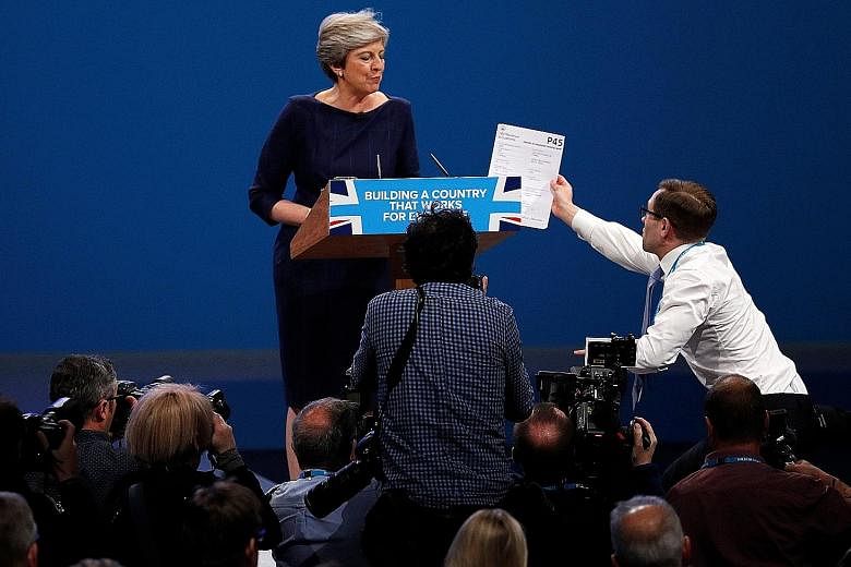 Comedian Simon Brodkin handing British Prime Minister Theresa May a P45 letter, a document given to employees when they leave their job, at the Conservative Party conference in Manchester yesterday.