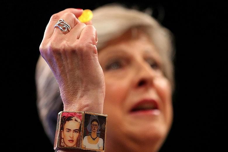 British PM Theresa May, with a bracelet bearing images of Mexican artist Frida Kahlo, holding a sweet passed to her after she was seized by a coughing fit as she addressed her party in Manchester on Wednesday.