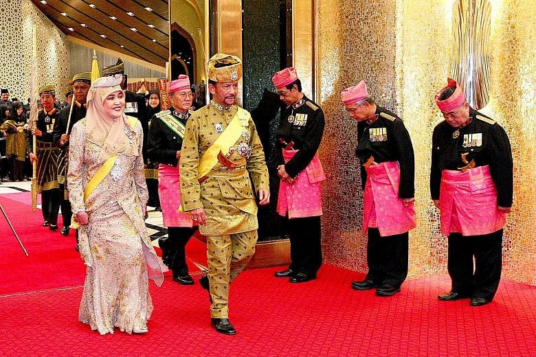 Above: Brunei Sultan Hassanal Bolkiah with his wife, Raja Isteri Pengiran Anak Hajah Saleha, at the throne hall of Istana Nurul Iman for the Golden Jubilee ceremony yesterday. Left: A huge crowd of people gathered in the streets of Bandar Seri Begawa