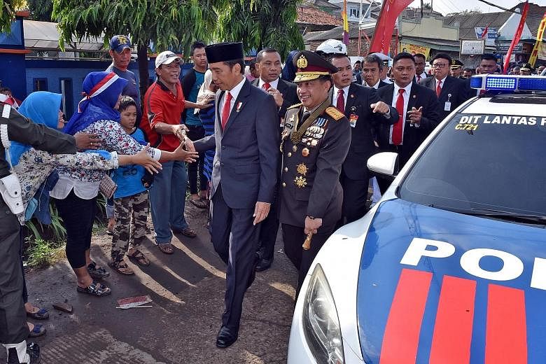 President Joko Widodo shaking hands with villagers as he walked the rest of the way - about 2km - to the venue for a military parade to mark the 72nd anniversary of Indonesia's national armed forces in Cilegon, Banten province, yesterday. He had got 