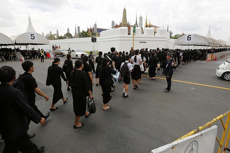 Thousands of Thais, dressed in mourning colours, lining up to pay their last respects to King Bhumibol Adulyadej outside the Grand Palace in Bangkok yesterday. The royal cremation will take place on Oct 26.