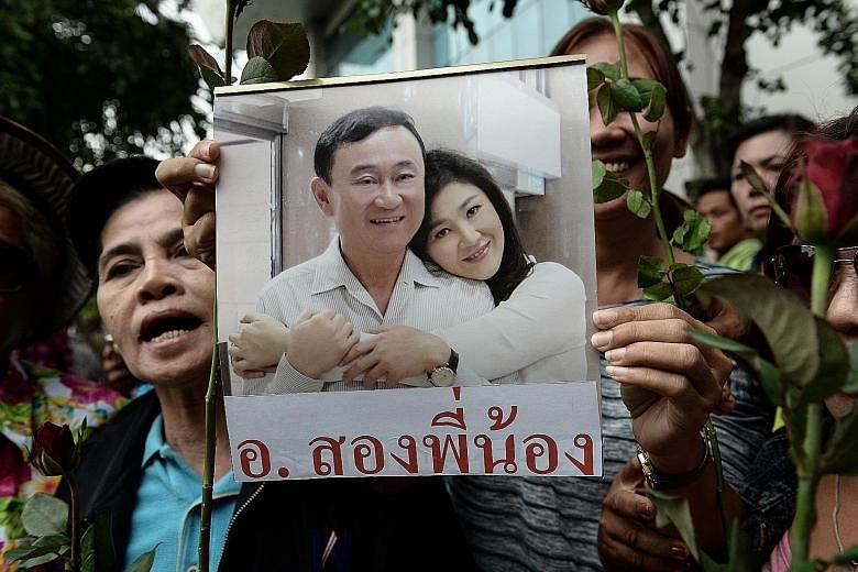 A woman holding a picture of former Thai prime ministers Thaksin and Yingluck Shinawatra. The military government has pursued supporters of the Shinawatras and has jailed several leaders of the political movement that backed them.