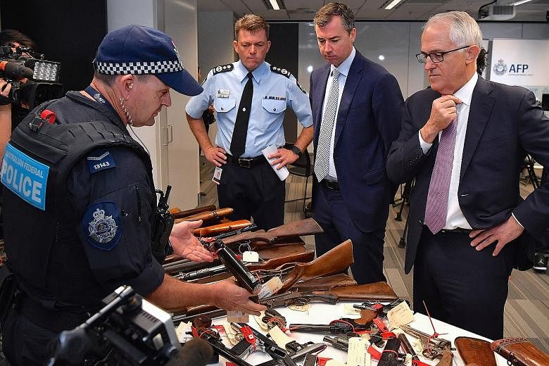 (From right) Prime Minister Malcolm Turnbull, Justice Minister Michael Keenan and Australian Federal Police Commissioner Andrew Colvin yesterday with some of the guns surrendered.