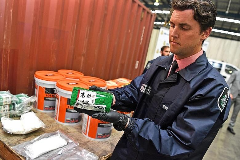 A police officer with a packet of liquid ephedrine at a press conference in Sydney yesterday. The 3.9-tonne haul of liquid ephedrine, concealed in a shipment of green-tea bottles from Thailand, is the biggest bust of the illegal substance in Australi