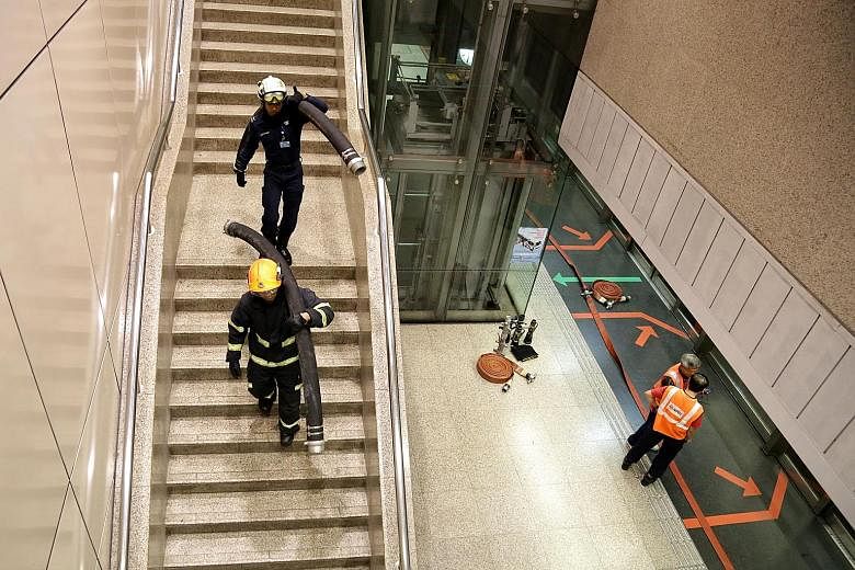 SCDF staff carrying equipment into Braddell station during yesterday's service disruption.