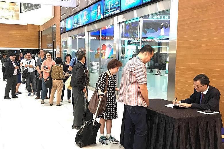 Mr Goh Eng Yeow signing copies of his latest book - Market Smart: How To Grow Your Wealth In An Uncertain World (above) - during its launch at the SGX Auditorium on Friday.