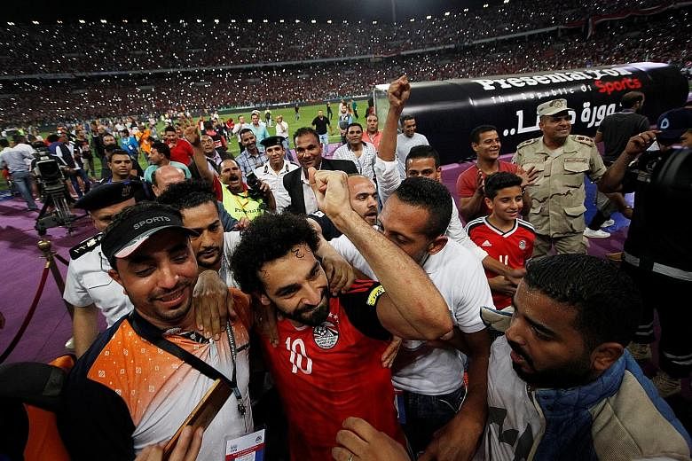 Above: Egypt winger Mohamed Salah (No. 10) celebrating the nation's entry into next year's World Cup Finals with his team-mates and fans at the Borg el-Arab Stadium on Sunday. The Pharaohs last took part in football's showpiece in Italy in 1990.
