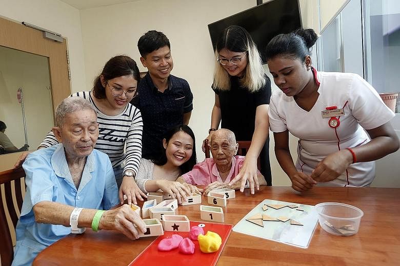 Patients Chan Wing Sum and Chong Cheng Moi try out the games created by (from second left) students Khaw June Ming, Cassandra Seah and Grace Goh. Looking on are Assistant Professor Michael Tan Koon Boon and staff nurse Nisanthi Sathasivam.