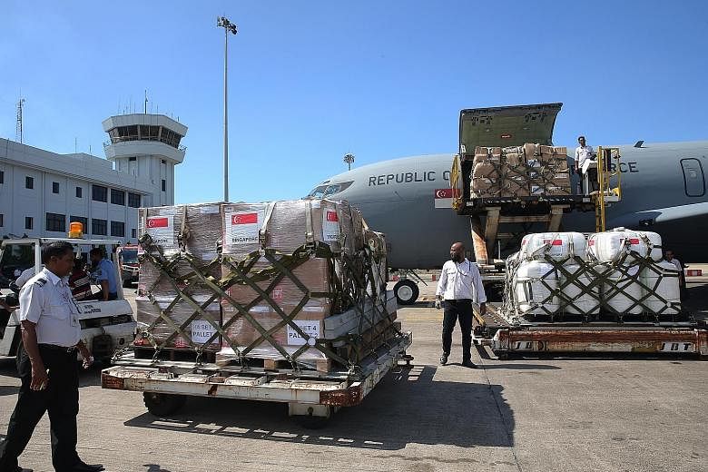 Above: Supplies being unloaded from the RSAF plane yesterday. Left: Senior Lieutenant-Colonel Lim Lit Lam handing over a box of aid to Chittagong Divisional Commissioner Md Abdul Mannan yesterday, along with Dr Maliki Osman. With them are (from far l