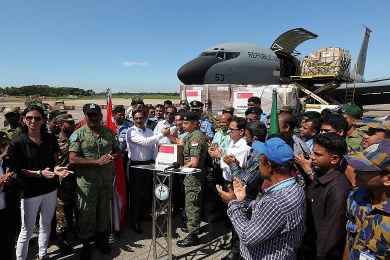Above: Supplies being unloaded from the RSAF plane yesterday. Left: Senior Lieutenant-Colonel Lim Lit Lam handing over a box of aid to Chittagong Divisional Commissioner Md Abdul Mannan yesterday, along with Dr Maliki Osman. With them are (from far l