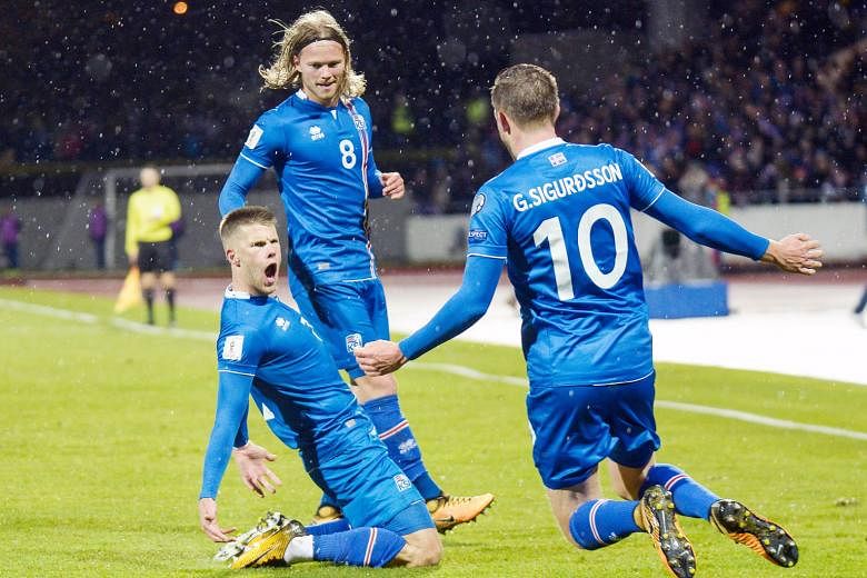 Iceland players celebrate after becoming the smallest nation to progress to a World Cup Finals, beating Kosovo 2-0 on Monday in Reykjavik. Johann Berg Gudmundsson, on his knees after scoring, is joined in his moment of glory by Birkir Bjarnason and G