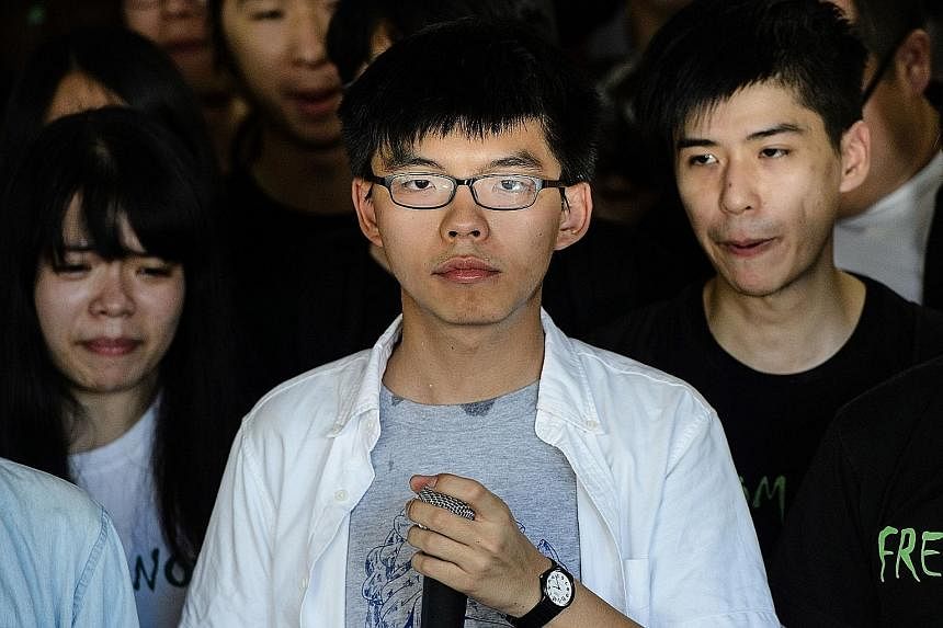 Pro-democracy activists gathering during a protest outside the High Court in Hong Kong yesterday. Supporters sang jailed pro-democracy leader Joshua Wong (above) a birthday song in the courtroom to mark his 21st birthday.