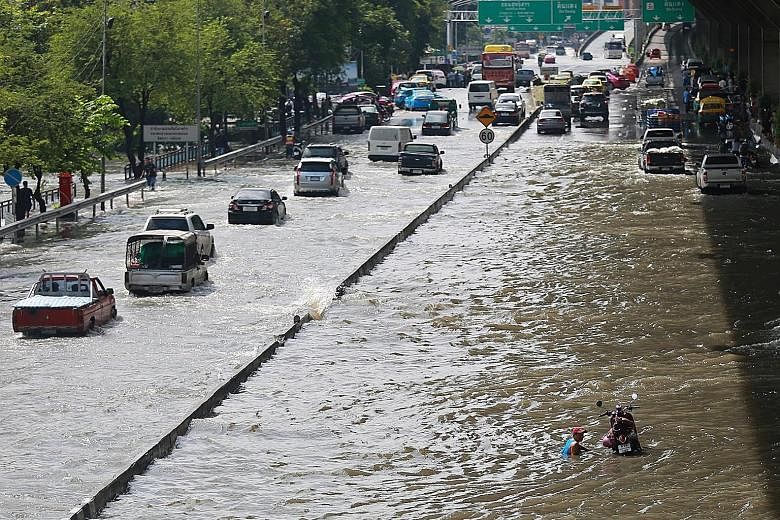 Vehicles struggling through a flooded street in Bangkok yesterday after overnight rain left many major roads submerged.