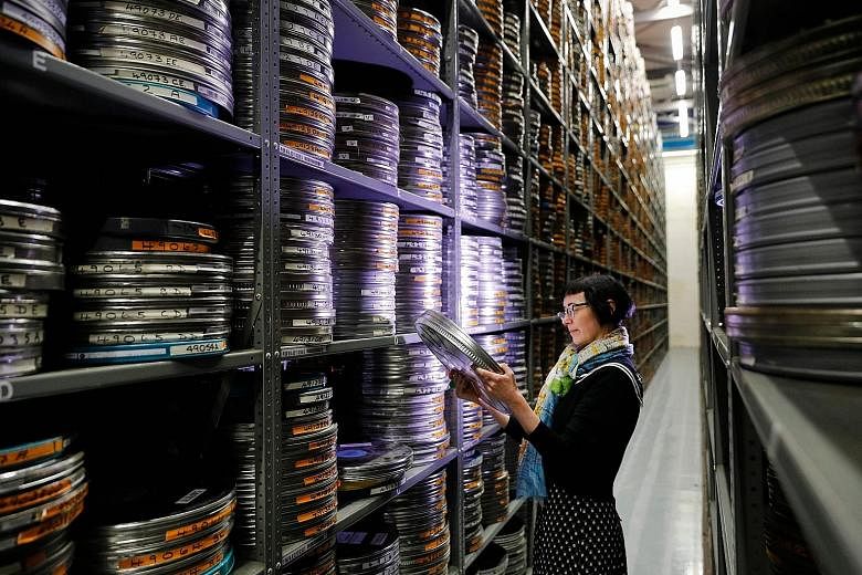 There are about 250,000 reels of old films in the storage archive (above) of the British Film Institute. Restoration work on old films include using the computer to digitally restore their individual frames. A conservation specialist with a roll of f