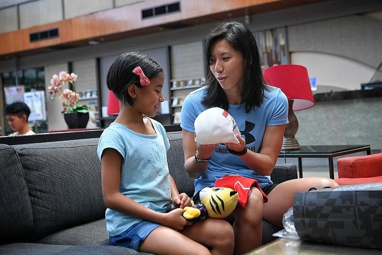 Amanda Lim, who has won every SEA Games 50m freestyle gold since 2009, giving Caitlin a gift bag containing a signed Rimau soft toy, swim cap and a Games jersey with a handwritten message on it.