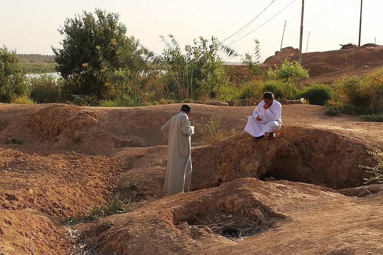 Iraqi men inspecting a pit containing the bodies of ISIS fighters in the town of Dhuluiyah, 90km north of Baghdad, last week.