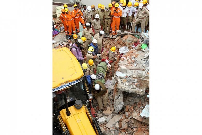 Fire brigade and National Disaster Response Force personnel removing the body of a victim who died when a two-storey building collapsed following a gas tank explosion in Bangalore yesterday.