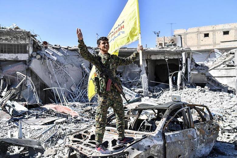 A member of the Syrian Democratic Forces celebrating at Raqqa's Al-Naim Roundabout after the SDF took full control of the Syrian city yesterday. The traffic circle became known as "Hell Roundabout" after ISIS used it for public executions.