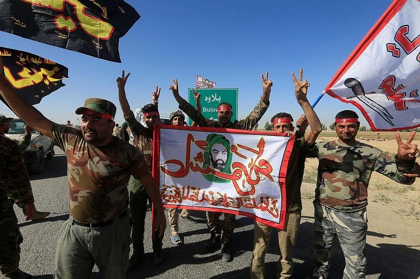 Shi'ite forces celebrating on the outskirts of Kirkuk yesterday. Iraqi forces and allied Iranian-backed militias have pressed their campaign to retake oil-rich territory from Kurdish forces, capturing the town of Sinjar.