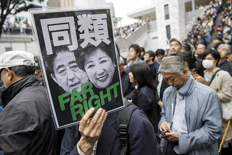A man holding up a sign featuring Japanese Prime Minister Shinzo Abe and Tokyo Governor Yuriko Koike under the words "same kind" at a rally for the CDPJ in Tokyo. The party's founder stresses commitment to individual civil rights, rather than obligat