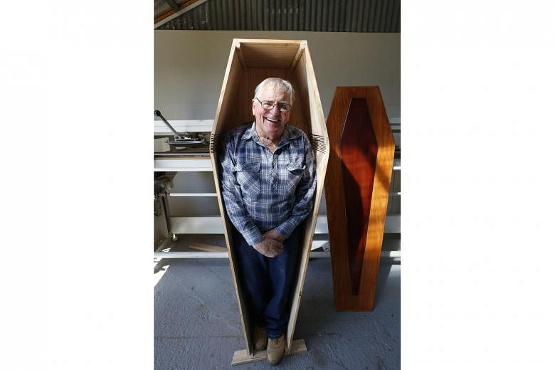 Mr Russell Game, 79, posing on Tuesday in his self-made coffin at the Community Coffin Club in Ulverstone, northern Tasmania. His wife is making the lining for the coffin, which is still to be finished. The coastal town of about 7,000 inhabitants boa