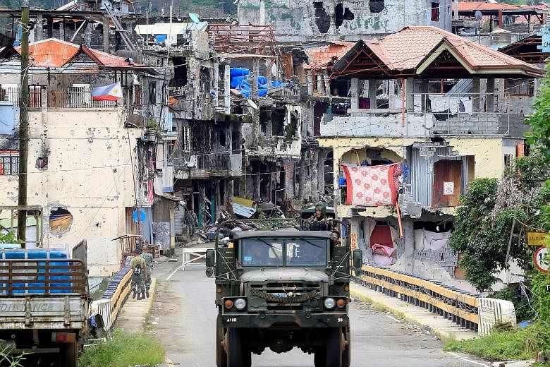 Soldiers driving a military truck through the war-torn city of Marawi yesterday. Defence Secretary Delfin Lorenzana estimates the Philippine government will need $1.5 billion to rebuild the city, which was liberated from terrorists after a nearly fiv