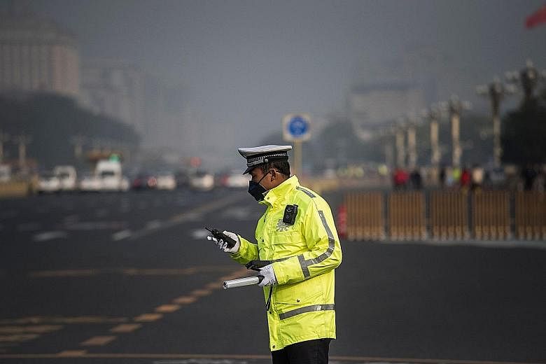 A policeman in a face mask at Tiananmen Square as smog enveloped Beijing yesterday, defying efforts to clear the air for the Chinese Communist Party's ongoing congress.