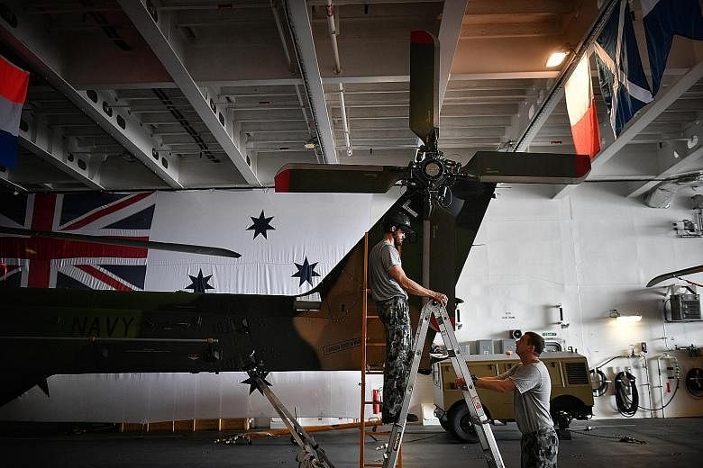 Members of the Royal Australian Navy working on an MRH-90 helicopter on board the HMAS Adelaide docked at Changi Naval Base. The Landing Helicopter Dock warship is the Australian navy's new amphibious vessel and was open to the media on its second da