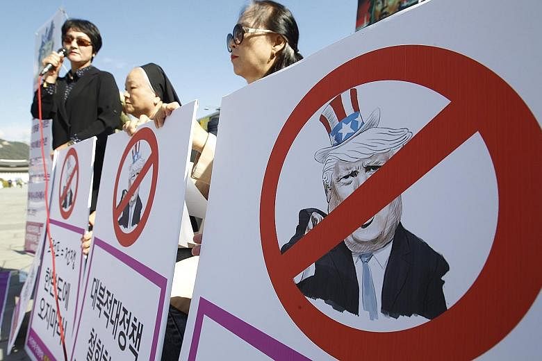 Civic activists with defaced portraits of US President Donald Trump during a rally outside the United States Embassy in Seoul on Thursday to protest against a joint American and South Korean naval exercise. South Korea is ramping up its defences agai